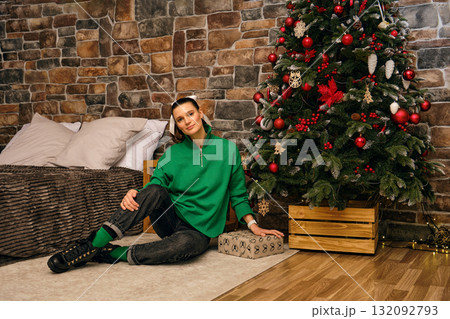 Cozy holiday setting with a joyful person by a decorated Christmas tree indoors 132092793