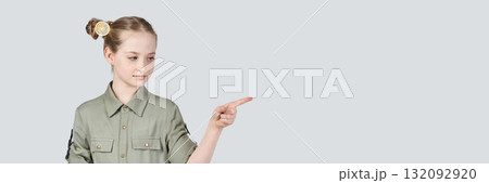 Caucasian young girl in green shirt pointing right with focused expression Caucasian young girl in green shirt pointing right with focused expression 132092920