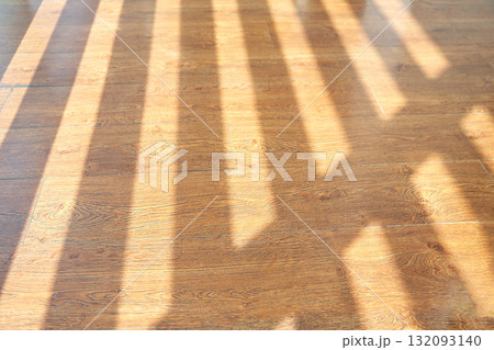 Sunlight streaming through window creating patterns on wooden floor 132093140