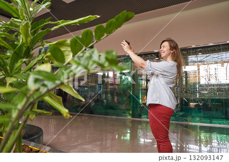 Caucasian female adult taking photos of indoor greenery in modern atrium Caucasian female adult taking photos of indoor greenery in modern atrium 132093147