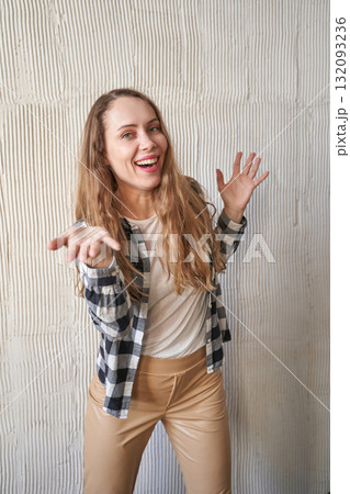 Caucasian young adult female joyfully posing in plaid shirt and beige pants 132093236