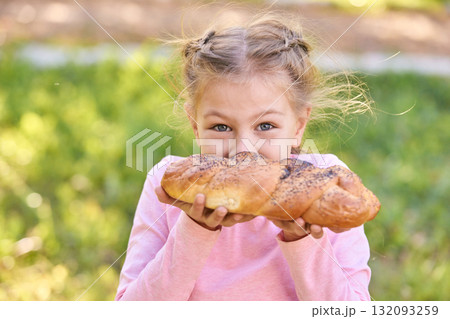 Caucasian blonde young girl enjoying fresh baked bread outdoors, smiling Caucasian blonde young girl enjoying fresh baked bread outdoors, smiling 132093259