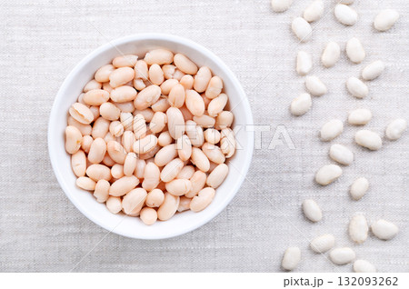 Cooked white beans, in a white bowl on linen. Boiled and canned cannellini beans, preserved white kidney beans, a variety of the common bean, Phaseolus vulgaris, and a vegetarian staple food. Photo 132093262
