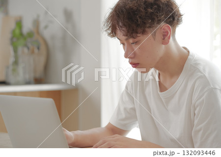 リビングでパソコン作業をする若い男性 リビングでパソコン作業をする若い男性 132093446