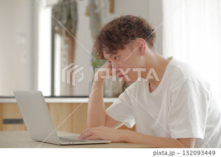 リビングでパソコン作業をする若い男性 132093449