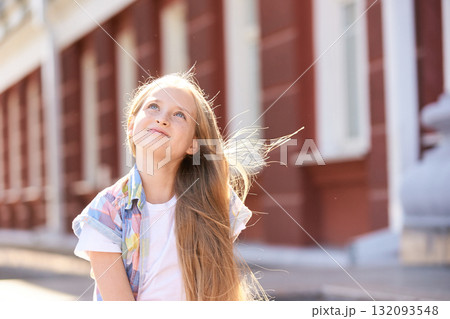 Smiling caucasian female child outdoors in sunny urban setting with long blonde 132093548