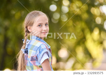 Caucasian young girl with braided hair outdoors in colorful plaid shirt looking 132093575