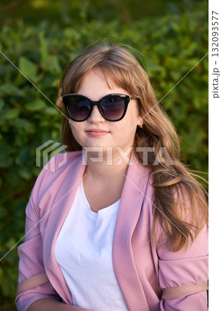 Caucasian young female in sunglasses and pink blazer relaxing outdoors Caucasian young female in sunglasses and pink blazer relaxing outdoors 132093577