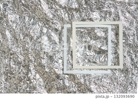 Geometric white squares on crumpled metallic silver foil background reflecting 132093690