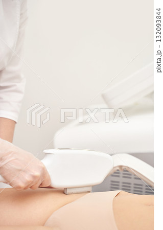 Female professional performing laser hair removal on leg in clinical setting 132093844