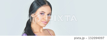 Young hispanic woman with long black hair in lavender top looking at camera 132094097