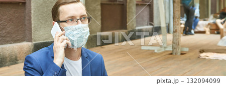 Caucasian adult male in blue suit with glasses wearing medical mask talking 132094099