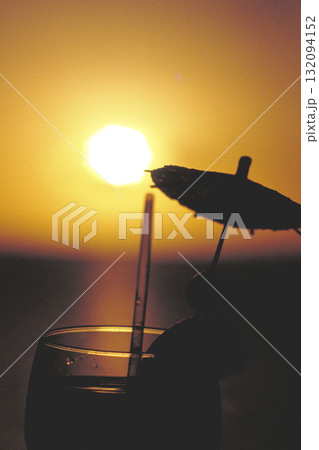 海に沈む夕日とカクテルのグラス 132094152