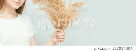 Young caucasian female holding pampas grass on a light background 132094304