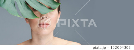 Caucasian adult female with leaf on face against neutral gray background Caucasian adult female with leaf on face against neutral gray background 132094305