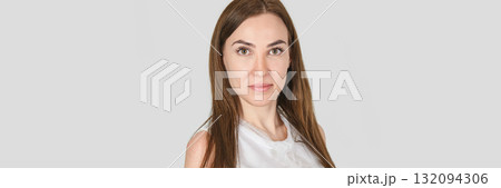 Young caucasian female with long brown hair wearing white top against gray Young caucasian female with long brown hair wearing white top against gray 132094306