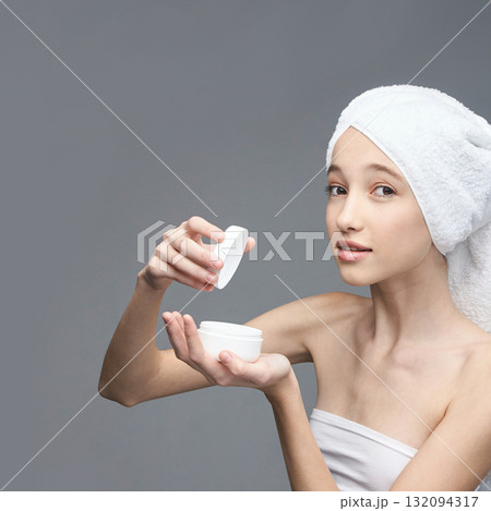 Young caucasian female applying skincare cream with white towel wrapped on head Young caucasian female applying skincare cream with white towel wrapped on head 132094317