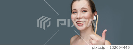 Caucasian female adult smiling holding eco-friendly bamboo toothbrush against Caucasian female adult smiling holding eco-friendly bamboo toothbrush against 132094449