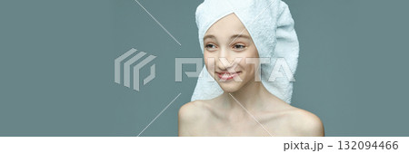 Young caucasian female with towel wrapped hair smiling against minimalist Young caucasian female with towel wrapped hair smiling against minimalist 132094466