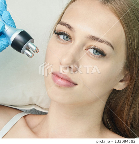 Young caucasian female receiving non-invasive beauty treatment in professional 132094582