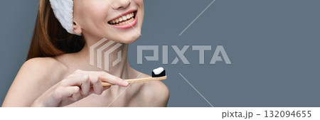 Young caucasian female using eco-friendly bamboo toothbrush with charcoal Young caucasian female using eco-friendly bamboo toothbrush with charcoal 132094655