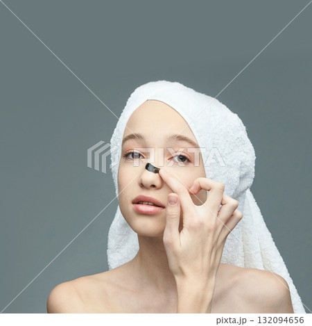 Young caucasian female applying nose strip for skincare routine with towel Young caucasian female applying nose strip for skincare routine with towel 132094656
