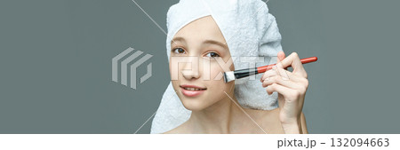 Young caucasian female applying makeup with brush after shower on clean face Young caucasian female applying makeup with brush after shower on clean face 132094663