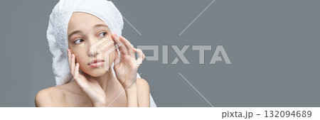 Young caucasian female applies gold eye patch for skincare routine on gray 132094689