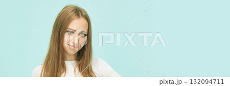Young caucasian female with long hair smiling against light blue background 132094711