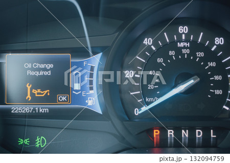 Close-up of a modern car dashboard, displaying an Oil Change Required warning light and message. Digital gauge cluster showing speedometer, fuel and battery status with high mileage Close-up of a modern car dashboard, displaying an Oil Change Required warning light and message. Digital gauge cluster showing speedometer, fuel and battery status with high mileage 132094759