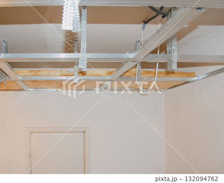 Suspended ceiling installation with metal frame and mineral wool for heat and sound insulation. 132094762
