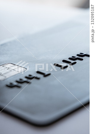 A close-up view of a black credit card with embossed numbers. The card is placed on a light surface, highlighting its sleek design and modern features. A close-up view of a black credit card with embossed numbers. The card is placed on a light surface, highlighting its sleek design and modern features. 132095187