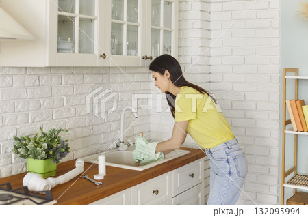Young woman trying to clear clog in sewer pipe with plunger, unblock sink drain Young woman trying to clear clog in sewer pipe with plunger, unblock sink drain 132095994