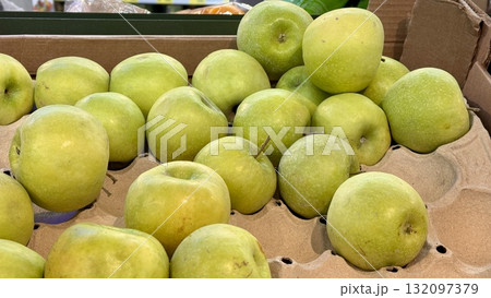 A vibrant and colorful display of fresh, crisp green apples organized neatly in a bustling market settings. Close-up. 132097379