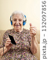 old senior woman listening music with blue headphones from smart phone 132097856