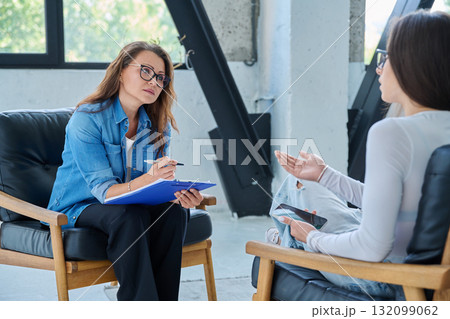 Middle aged professional female psychologist, counselor working with young woman Middle aged professional female psychologist, counselor working with young woman 132099062