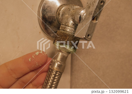 Female hand on an old, oxidized water faucet with hose: moisture damage and limescale 132099621