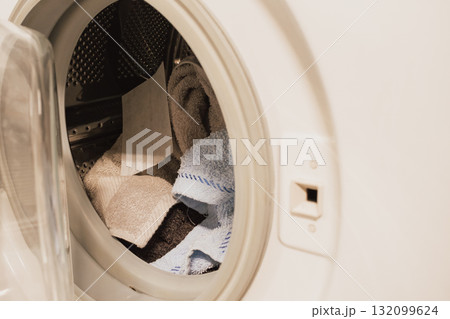White dye-catcher sheet lying in a washing machine drum with mixed laundry before wash 132099624
