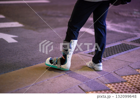 Person with Medical Boot on City Street at Night 132099648