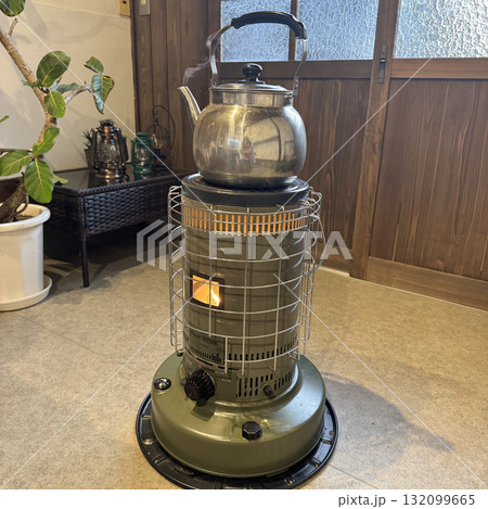 レトロな石油ストーブの上でやかんが湯気を立てる レトロな石油ストーブの上でやかんが湯気を立てる 132099665