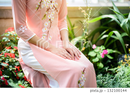 Portrait of Asian girls with Ao-Dai Vietnam traditional dress costume sitting in flower garden Portrait of Asian girls with Ao-Dai Vietnam traditional dress costume sitting in flower garden 132100144