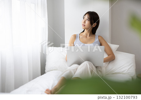 ベッドの上でノートパソコンを操作する若い女性 ベッドの上でノートパソコンを操作する若い女性 132100793