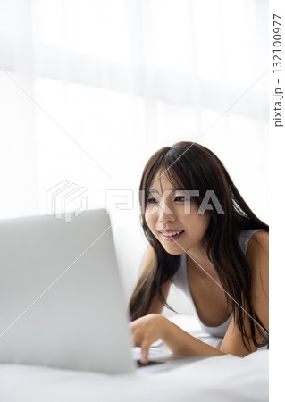 ベッドでパソコンを操作する若い女性 132100977