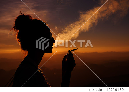 silhouette of smoking woman in sunset landscape 132101894