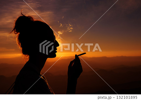 silhouette of smoking woman in sunset landscape 132101895