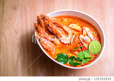 Thai hot spicy soup shrimp in coconut milk or Tom Yum Goong on wooden table 132101914