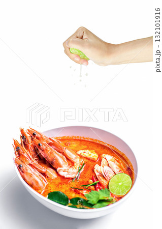 Hand Squeezing slice half Lime on Hot spicy shrimp soup in coconut milk or Tom Yum Goong on white background , Thai food Hand Squeezing slice half Lime on Hot spicy shrimp soup in coconut milk or Tom Yum Goong on white background , Thai food 132101916