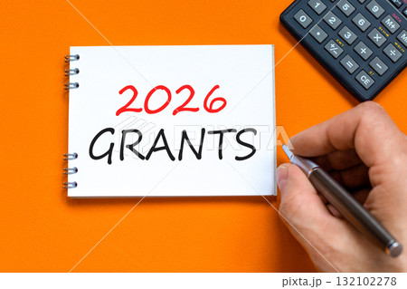 2026 Grants symbol. Concept words 2026 Grants on beautiful white note. Black calculator. Beautiful orange paper background. Businessman's hand. Business and 2026 grants concept. Copy space. 132102278