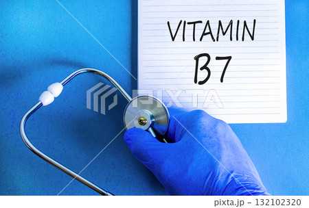 Vitamin B7 biotin symbol. Concept words Vitamin B7 on beautiful white note. Doctor's hand in blue medical glove. Stethoscope. Beautiful blue background. Medical healthy lifestyle Vitamin B7 concept. 132102320