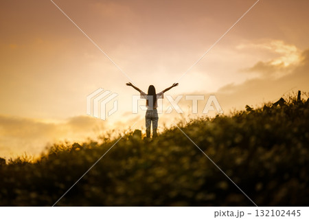 silhouette of happy woman relaxing on mountain hill in summer sunset sky happy girl enjoying freedom and life raising arms feeling free silhouette of happy woman relaxing on mountain hill in summer sunset sky happy girl enjoying freedom and life raising arms feeling free 132102445